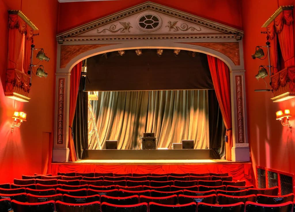 Small theatre with a red front curtain drawn back at the sides