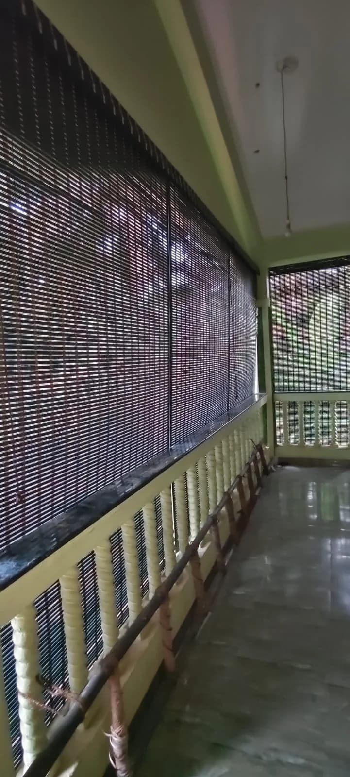Bamboo blind lowered along a balcony railing, seen from inside