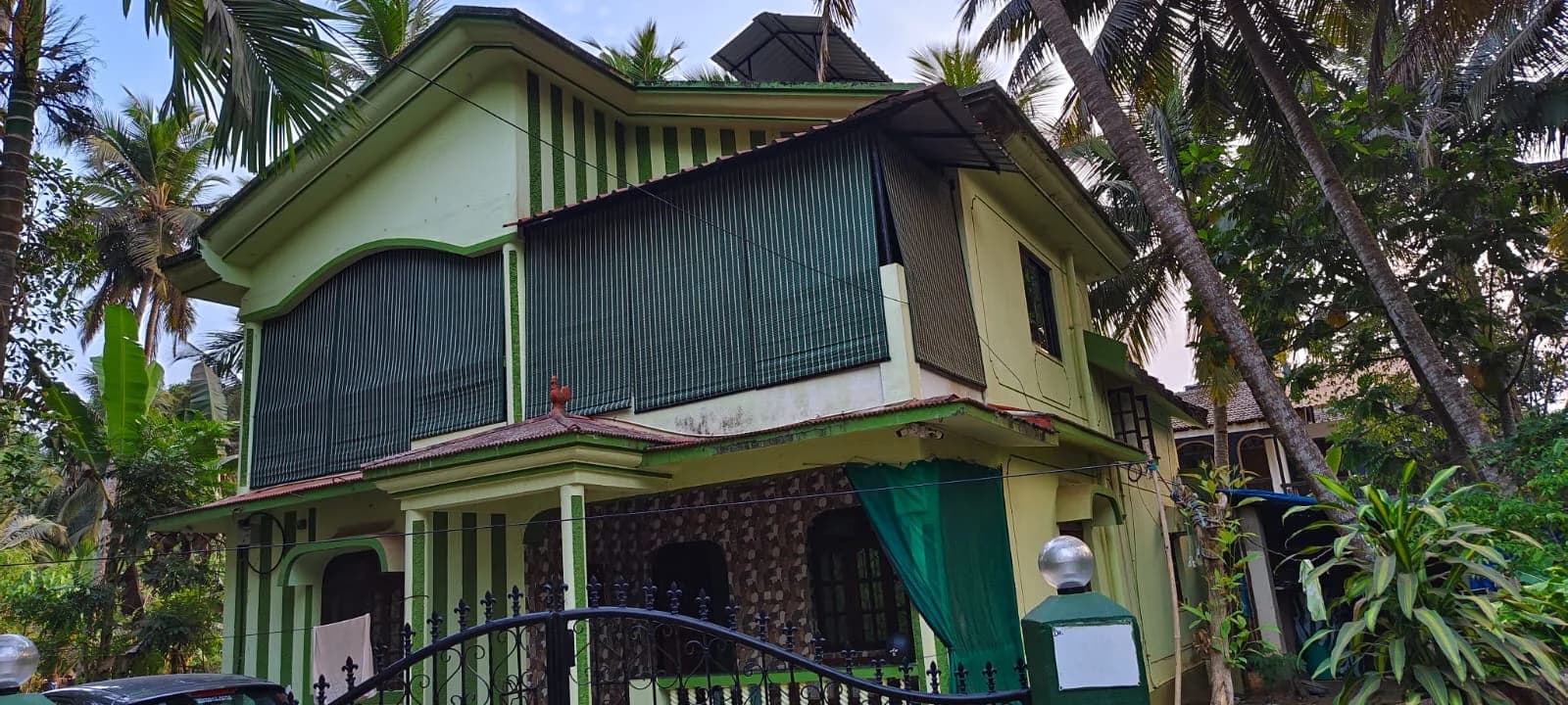 House seen from the road with bamboo blinds on the upper balcony