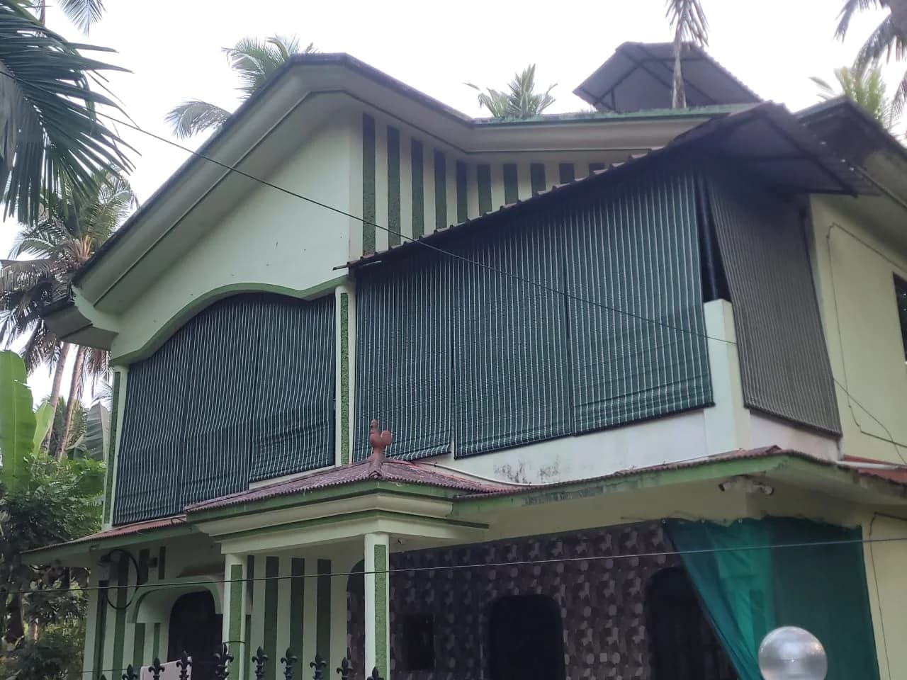 House in Panjim with bamboo blinds lowered across the first-floor balcony