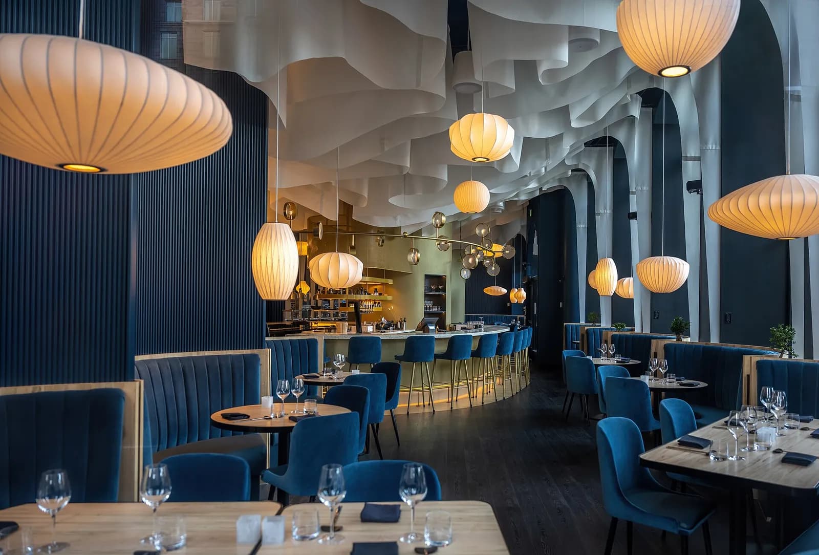 Restaurant dining room with blue upholstered seating and pendant lights