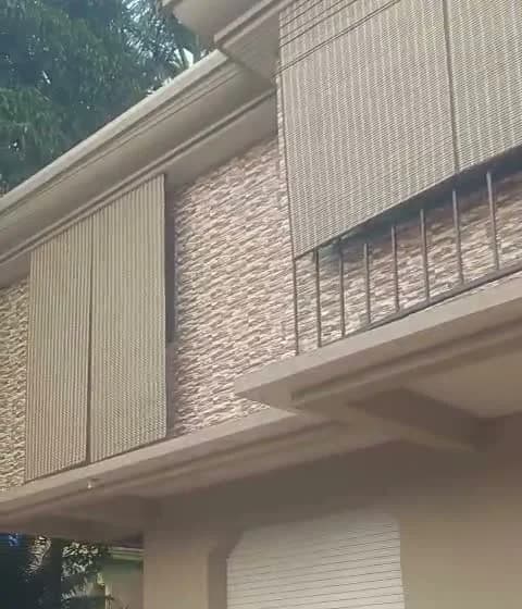 Pair of PVC chick blinds outside a first-floor opening on the side of the building in Margao